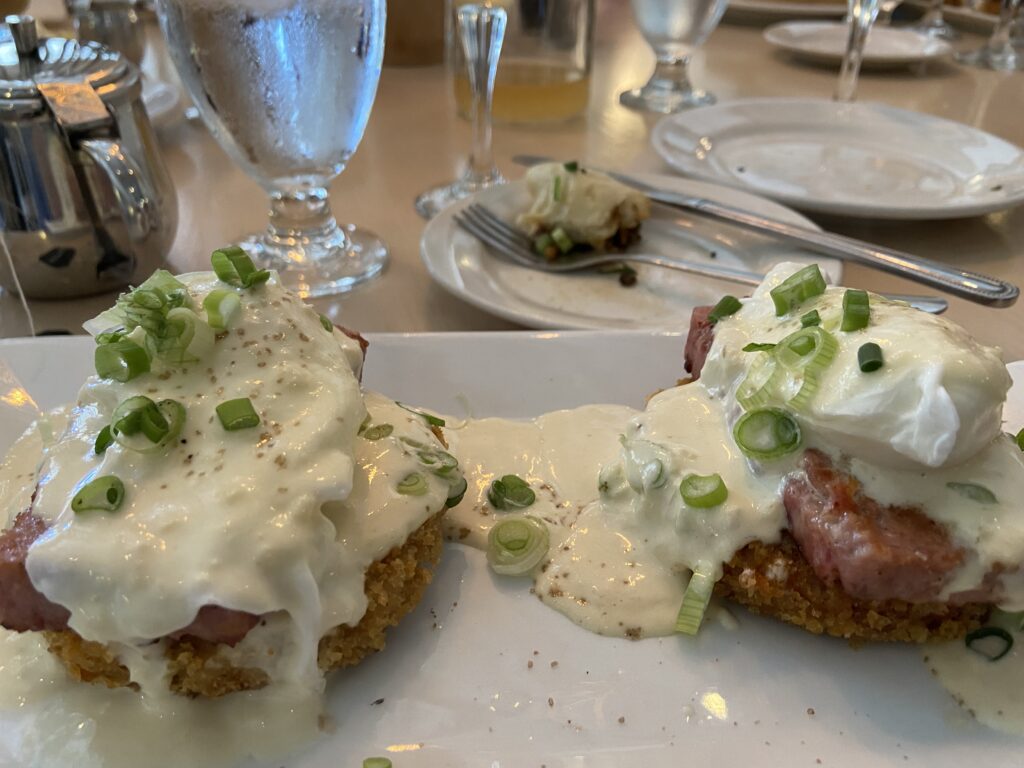 Two Kau Kau Benedict’s. On top of crispy taro cakes are homemade spam, poached egg, and sesame miso hollandaise sauce with green onions.
