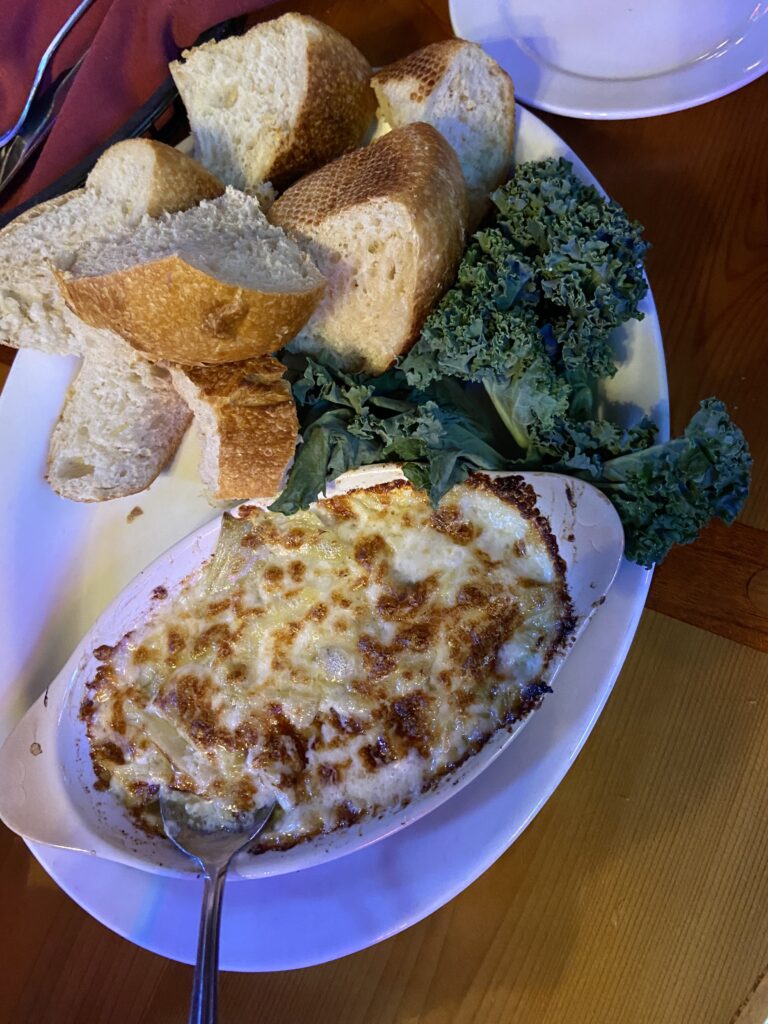 Artichoke cheese dip with bread and green lettuce on the side