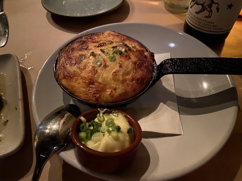 Tortilla Espanola. A baked egg and potato omelette with green onion on top and a side of Crème and green onion.
