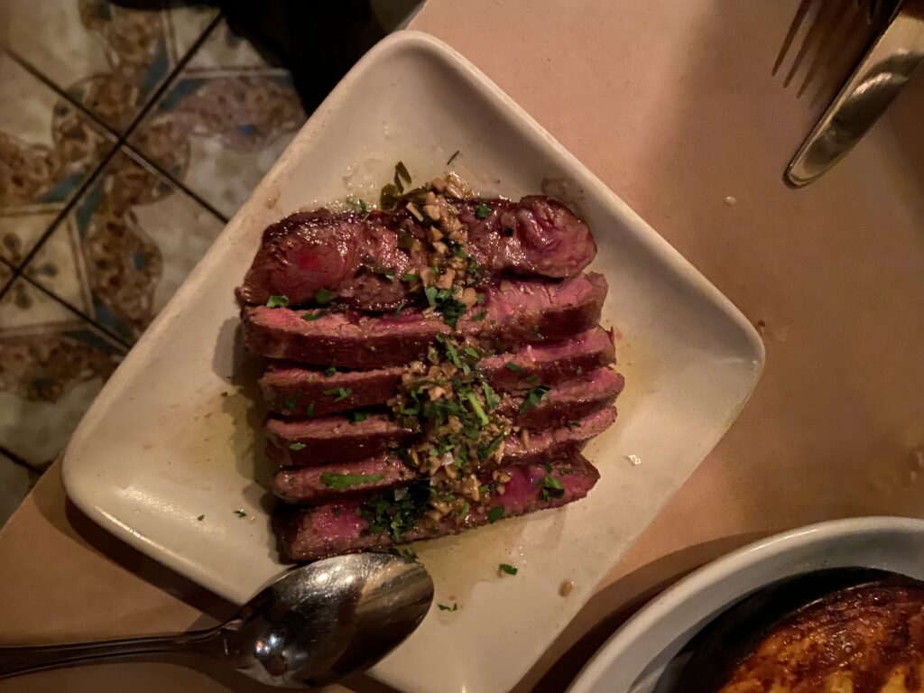 Akaushi Flat-Iron Steak cooked medium rare with chimichurri sauce on top.