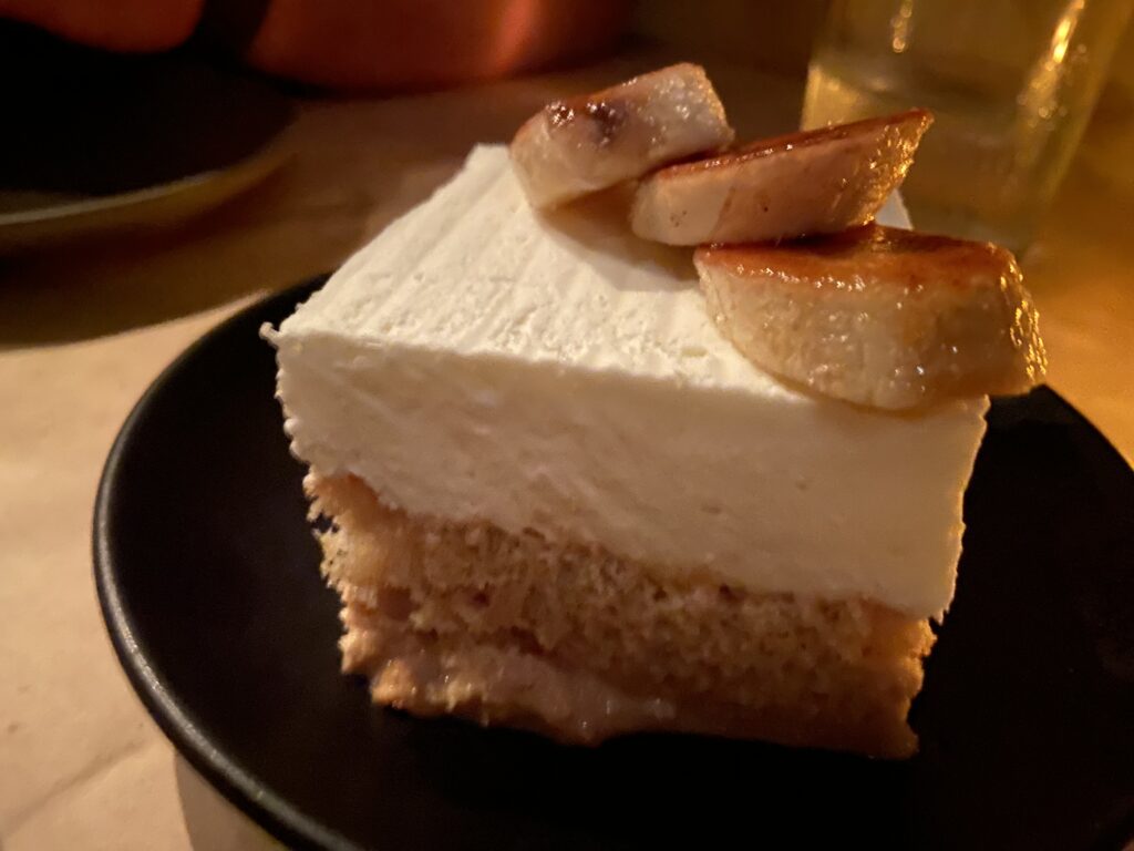 Pastel de Tres Leches with a cream layer on top, topped with three caramelized banana slices.