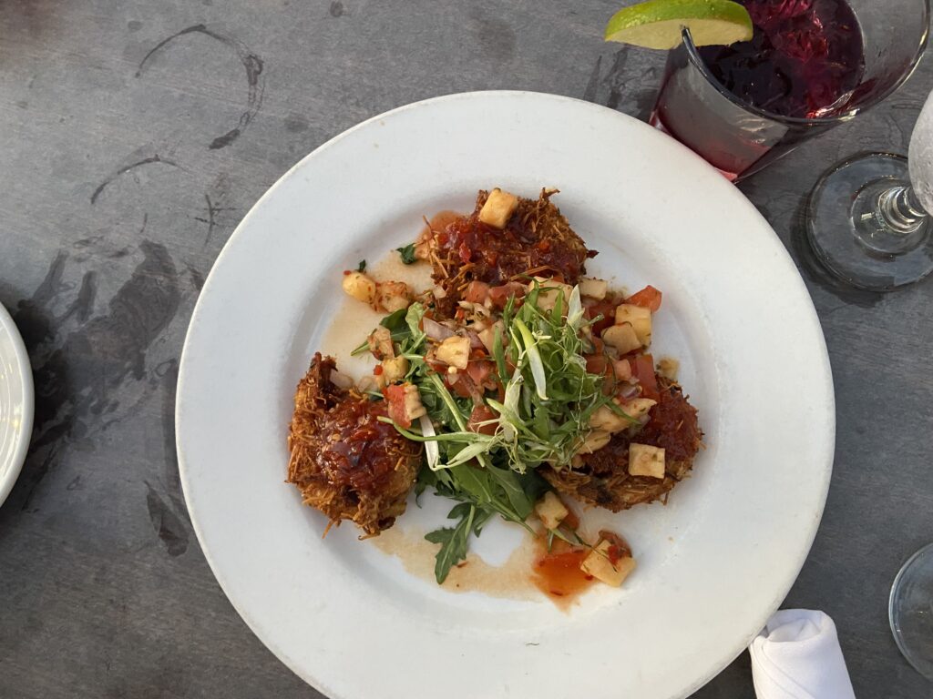 Coconut shrimp appetizer. Three coconut breaded shrimp with an apple, tomato slaw with arugula on top.