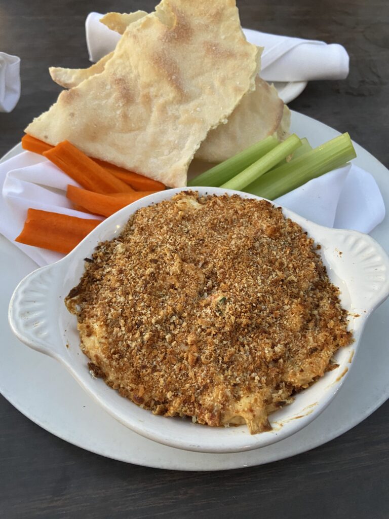 Spinach & Artichoke dip with tortilla chips, celery sticks, and carrot sticks.
