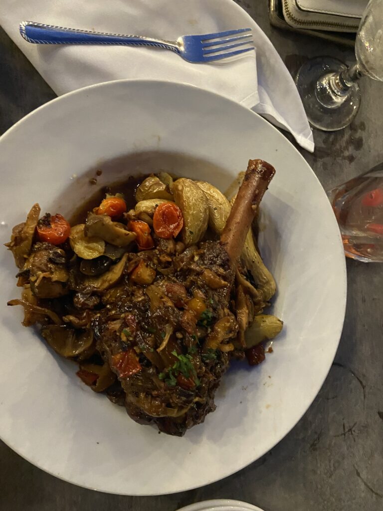 Leg of Lamb with wedge potatoes and roasted vegetables and garlic on top.