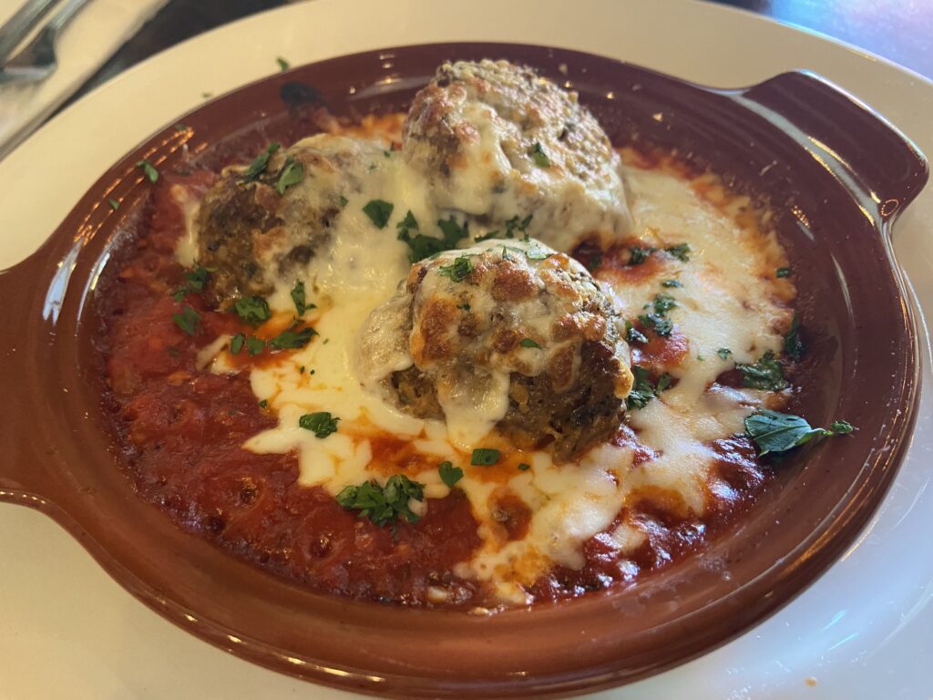 three meatballs with marinara sauce topped with cheese.